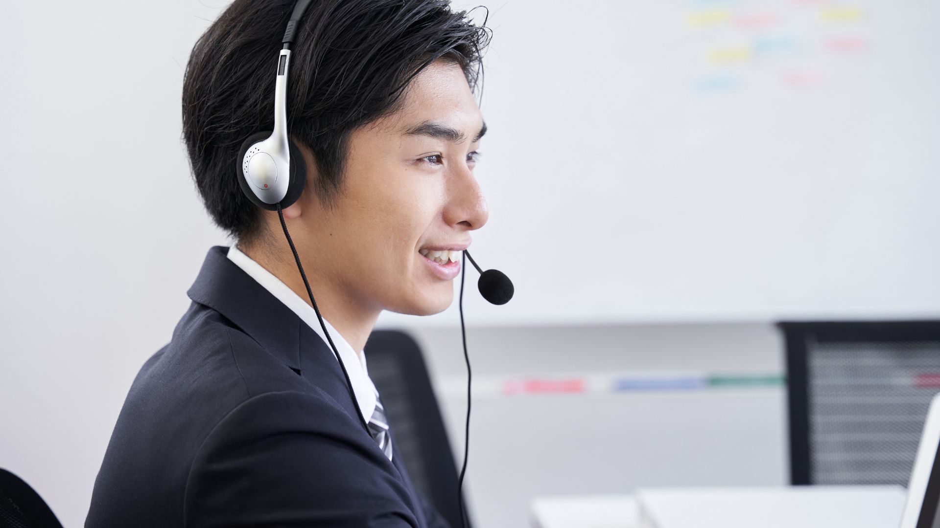 ヘッドセットをつけた男性オペレーターが笑顔で対応している様子