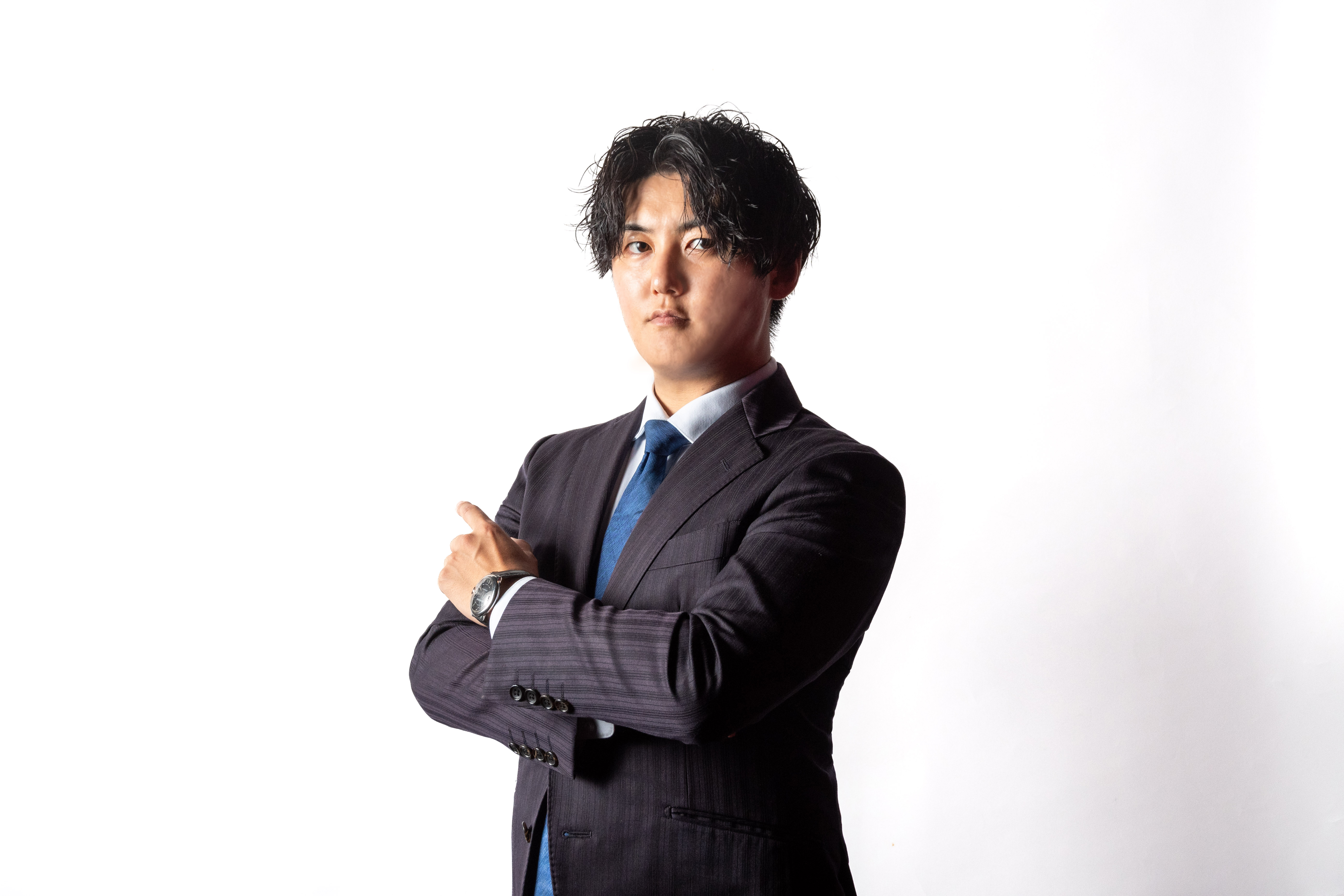 株式会社Growth Partners Japan 取締役 島田竜齊の公式写真。ネイビーのスーツで腕を組み、真剣な表情で前を見据えている。